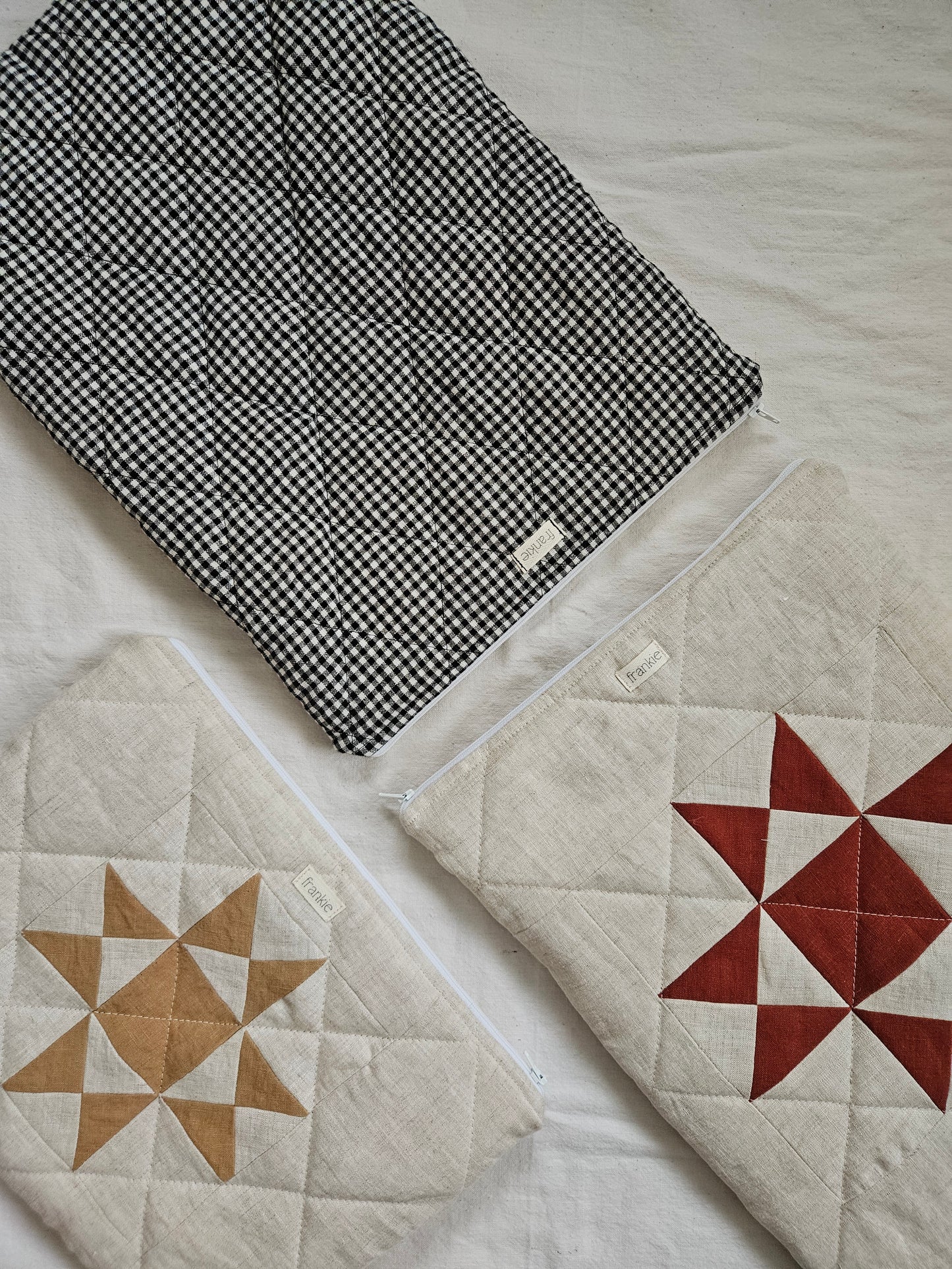 Two quilted items on a textured surface, one with a black and white pattern and the other with star designs.